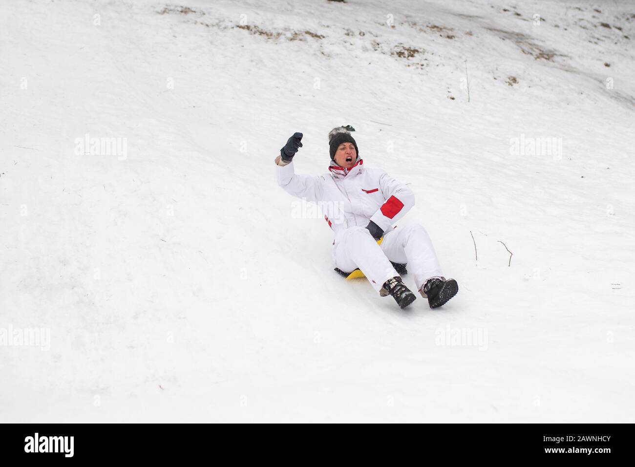 Una mujer adulta monta en trineos de hielo desde la montaña. Diversión emocionalmente.Winter. Foto de stock