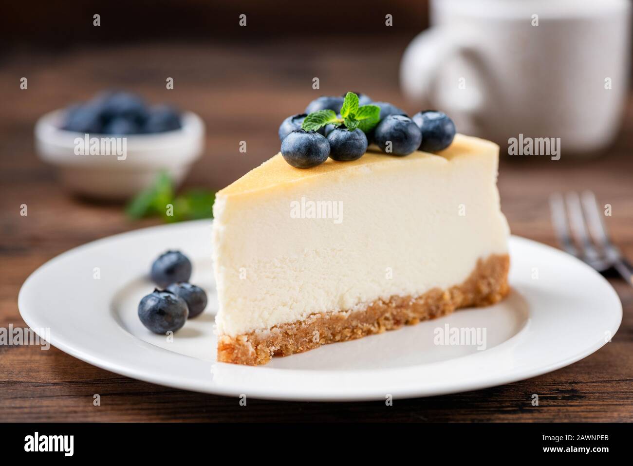 Corte de tarta de queso con arándanos en placa blanca, fondo de mesa de madera. Sabroso postre dulce. Tarta De Queso Clásica De Nueva York Foto de stock