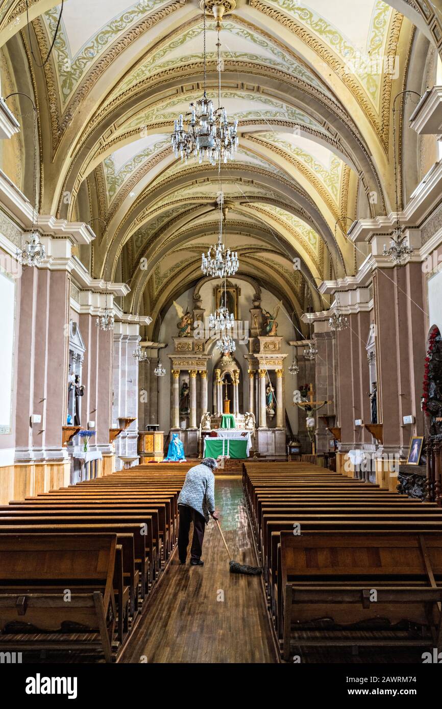 Una mujer barre el piso en la antigua iglesia Parroquia de San Simón Apostol en Angangueo Una mujer barre el piso en la antigua iglesia Parroquia de San Simón Apostol en Angangueo