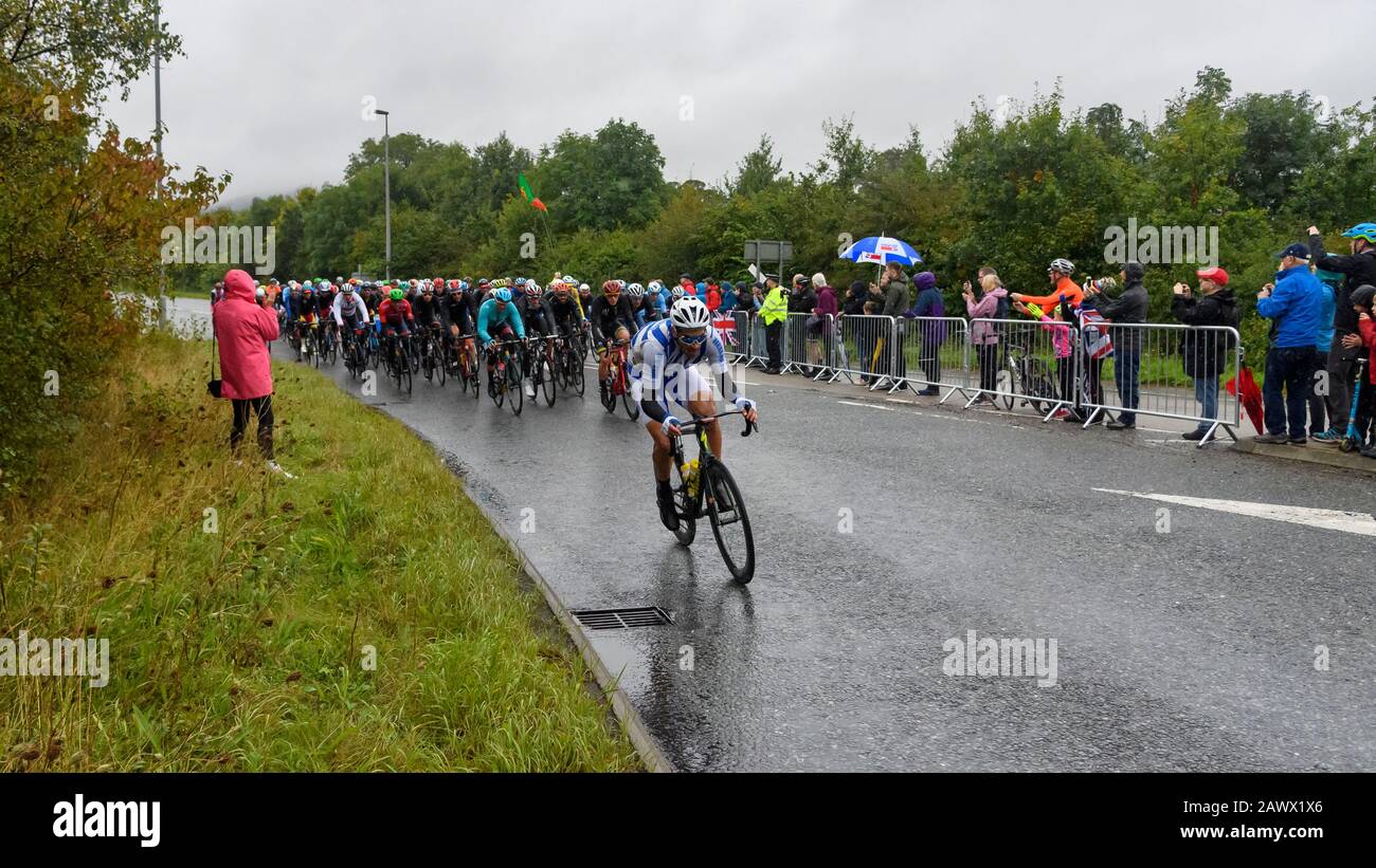 Hombres carreras de bicicletas de carretera (ciclistas pelotón en bicicletas) montar y competir en la carrera vigilada por los aficionados mojados en la lluvia - Campeonato del Mundo UCI, Yorkshire Reino Unido Foto de stock