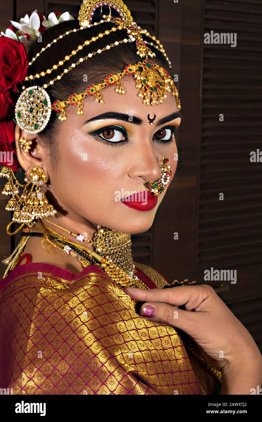 Mujer joven hindú modelo con sari de seda roja y joyas de oro y brazaletes  conjunto. Perfil lateral Fotografía de stock - Alamy