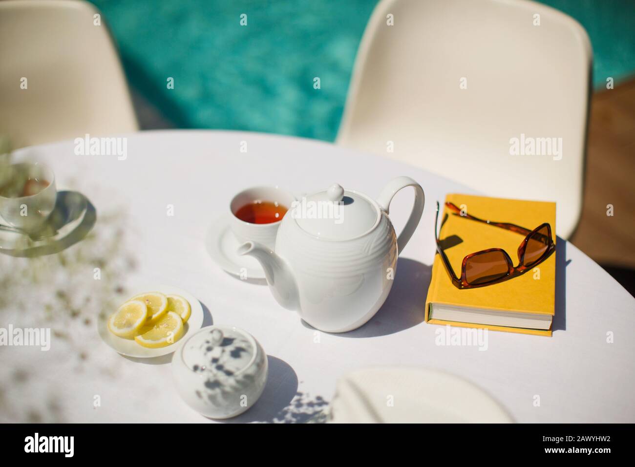 Servicio de té y reserva en mesa soleada junto a la piscina Foto de stock