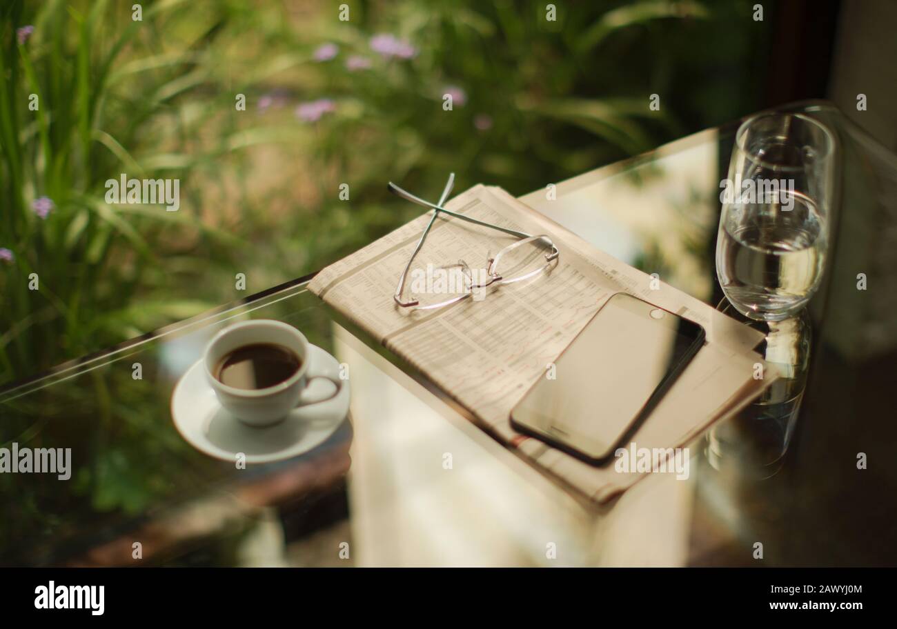 Teléfono inteligente y bolsa de prensa en la mesa con café Foto de stock