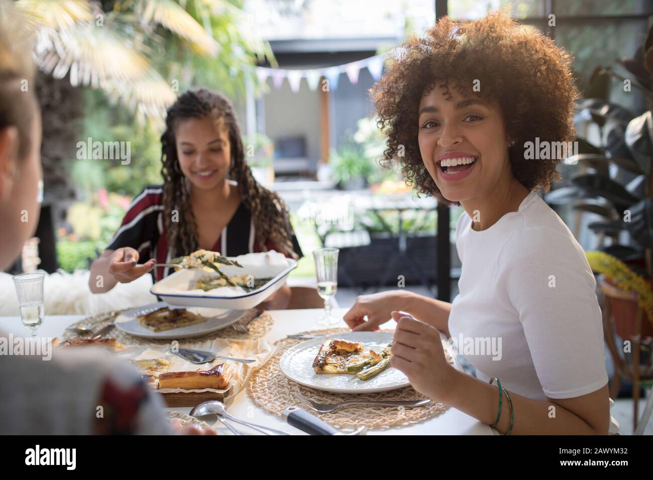 Retrato Feliz mujer joven comer almuerzo con amigos en la mesa Foto de stock