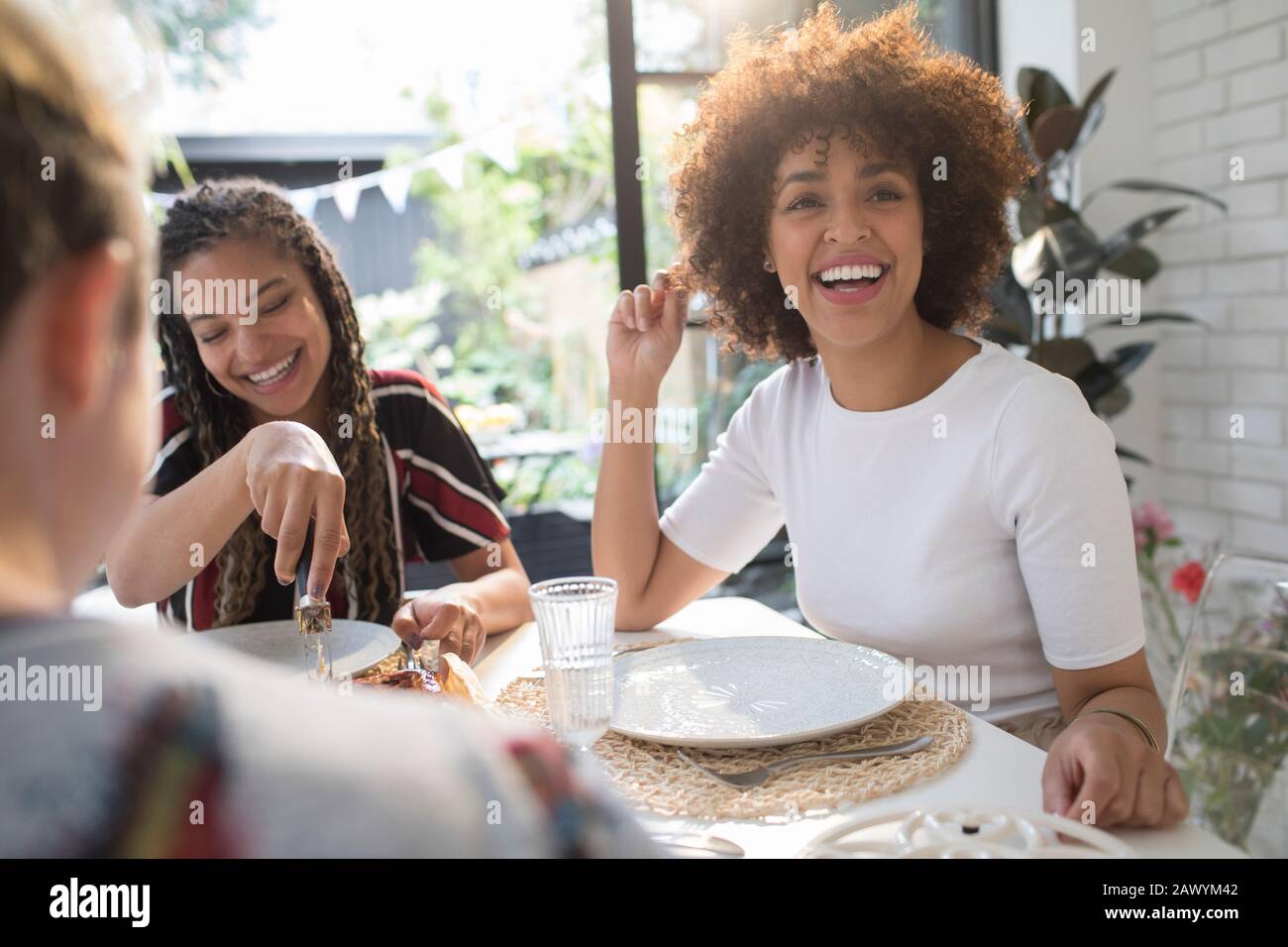 Felices mujeres jóvenes amigos disfrutando de la comida en la mesa de comedor Foto de stock