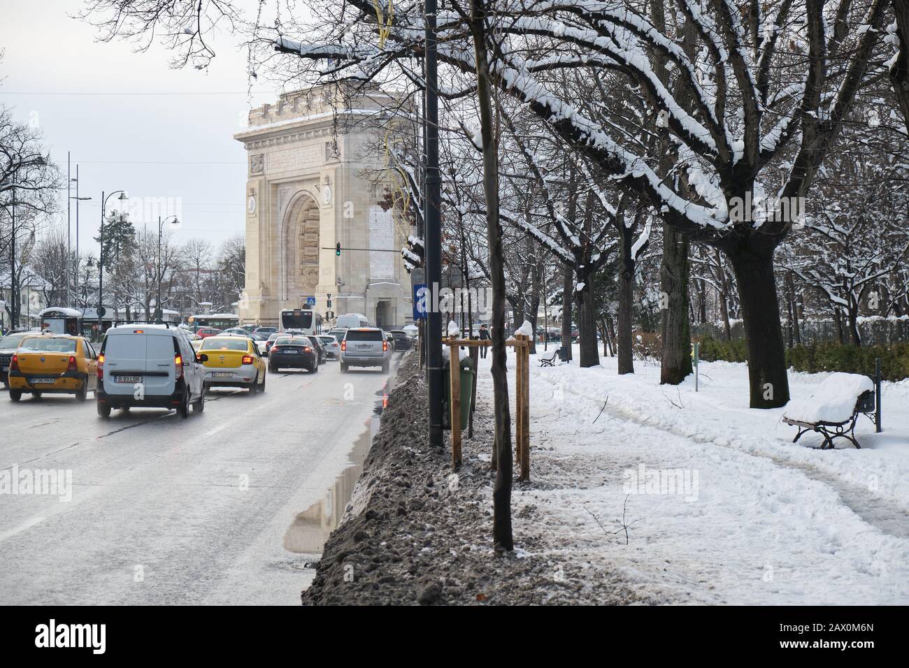 Bucarest, Rumania - 6 de febrero de 2020: Contraste entre una carretera de automóviles despejada y una acera cubierta de nieve con un sendero estrecho hecho por los peatones, en Foto de stock