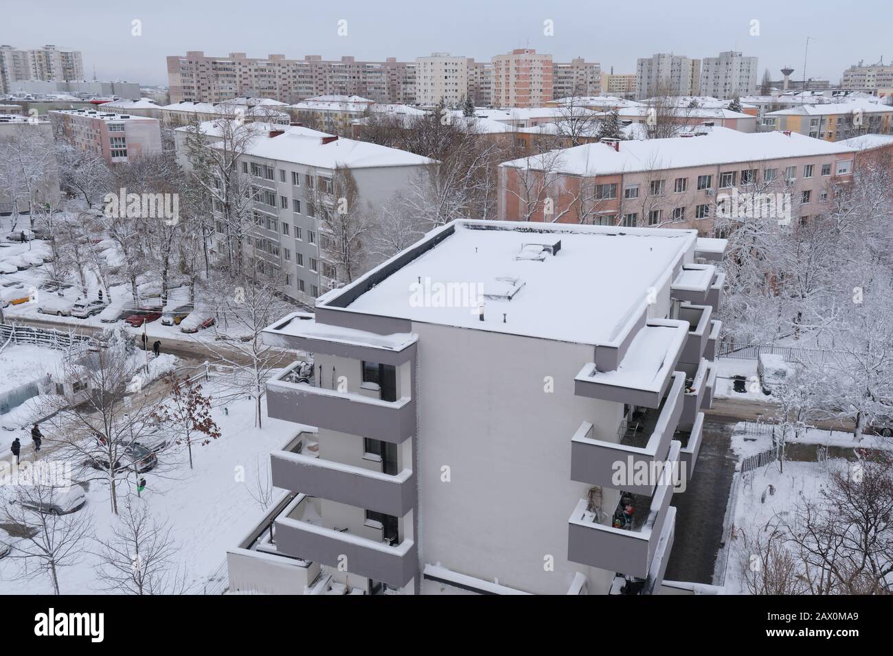 Bucarest, Rumanía - 6 de febrero de 2020: Escena invernal en una zona residencial con edificios de bloques de apartamentos nuevos y antiguos, con tejados cubiertos de nieve, en Buch Foto de stock