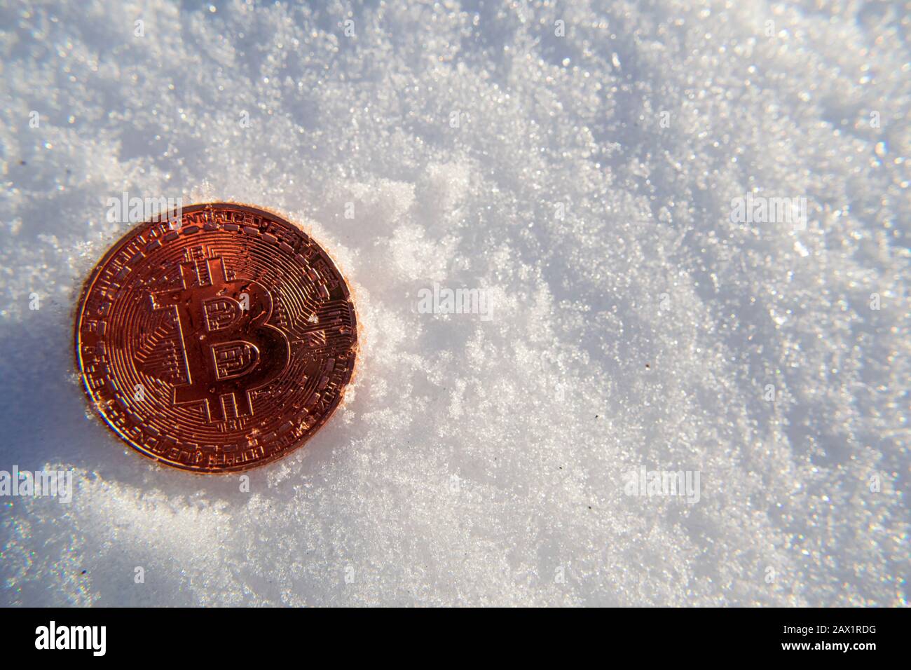 La moneda de oro de Bitcoin criptomoneda se congela en la nieve bajo el sol esperando a derretirse y descongelarse. El precio rompe la zona de congelación Foto de stock
