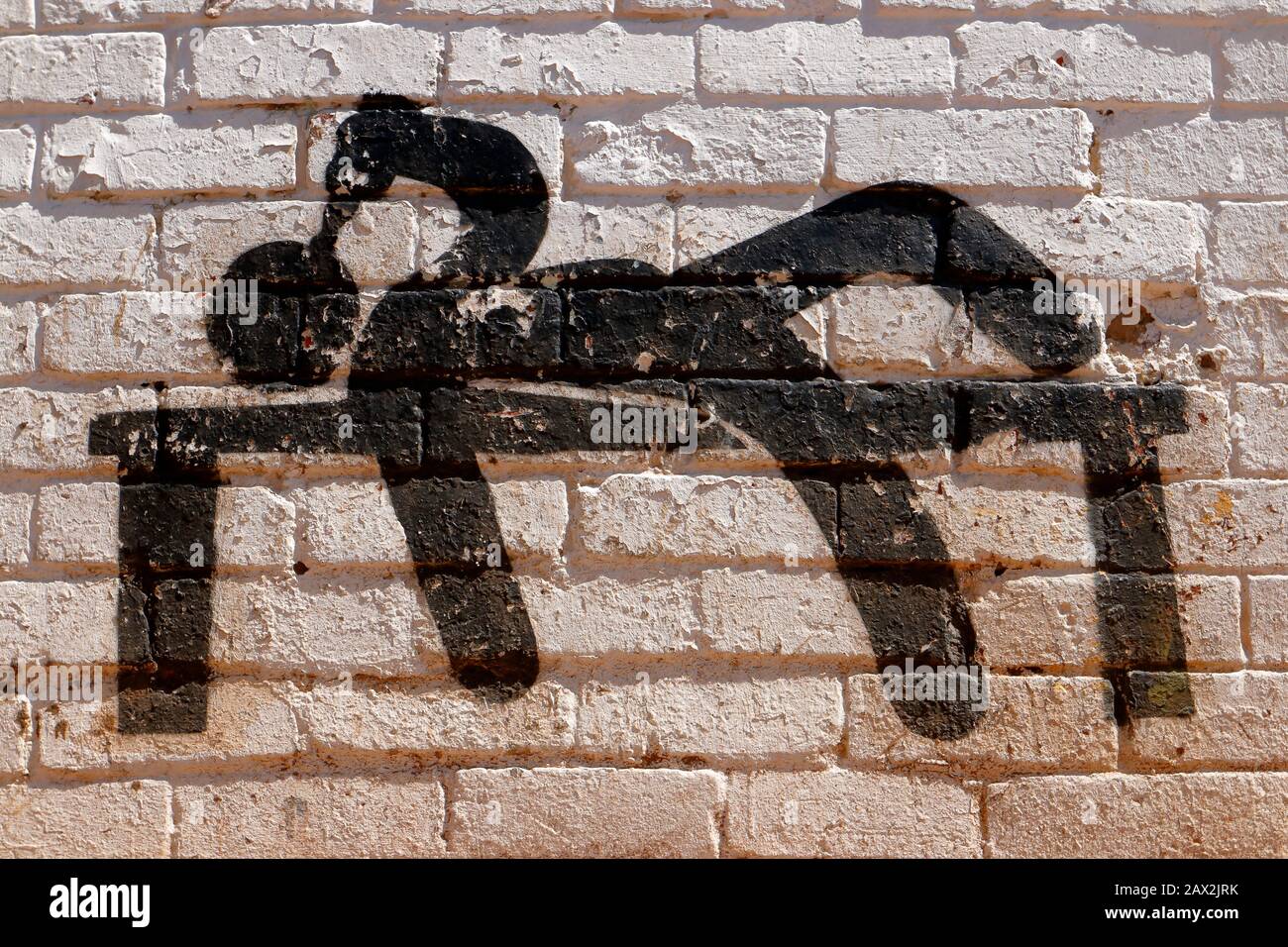 Mural de arte callejero en forma de silueta que representa a un hombre borracho acostado en un banco buscando consuelo y bebiendo en un estupor Foto de stock
