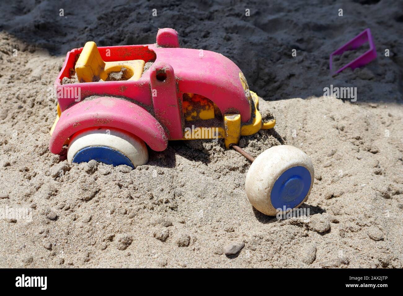¡las ruedas se apagaron! Atascado en un ruto, este tractor de juguete en la fosa de arena parece haber encontrado la misión pesada ir y ha arrojado en la toalla Foto de stock