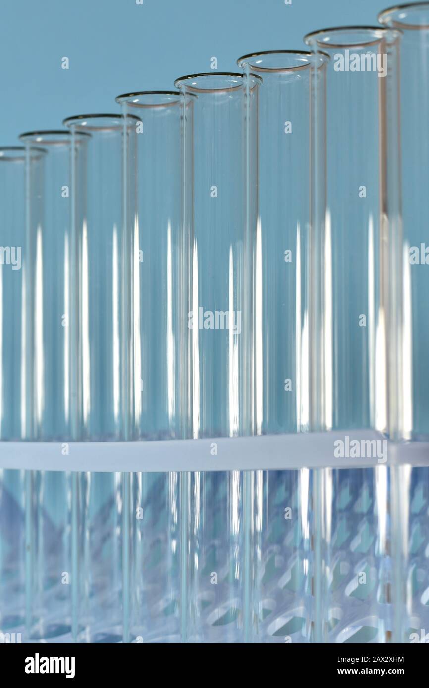 Imagen vertical de los tubos de ensayo transparentes extraídos de la bandeja sobre un fondo azul. Foto de stock