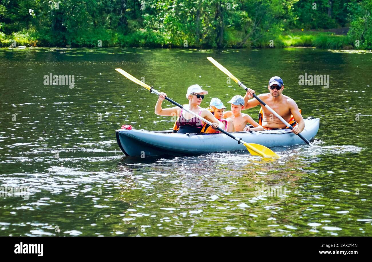 Una familia joven con un hijo y una hija están haciendo kayak en el lago Foto de stock