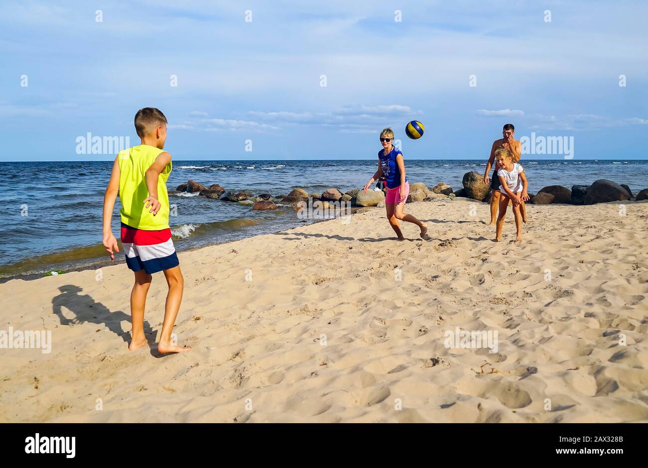 Una familia con un hijo y una hija jugando con una pelota en la playa Foto de stock