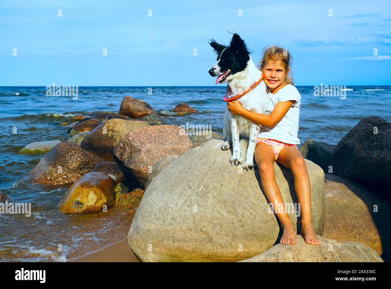 Niña con un perro en el lago abrazándose. Foto de stock