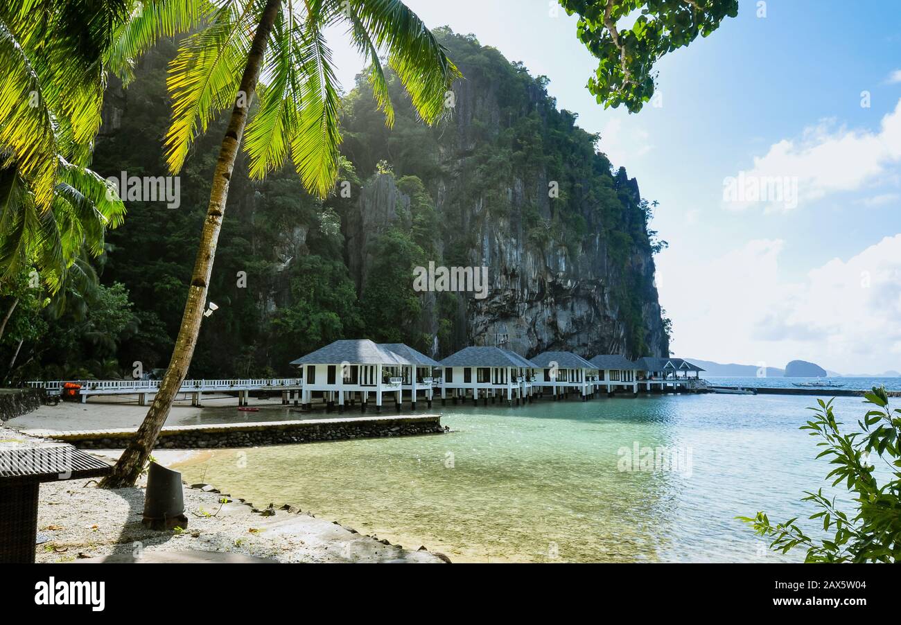 Cabañas de playa a la sombra de gigantescos afloramientos de piedra caliza - el Nido, Palawan, Filipinas Foto de stock
