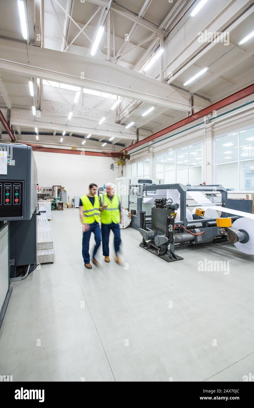 Movimiento desenfocado de los trabajadores en chalecos reflectantes entre modernas en fábrica de impresión con buena iluminación de stock - Alamy