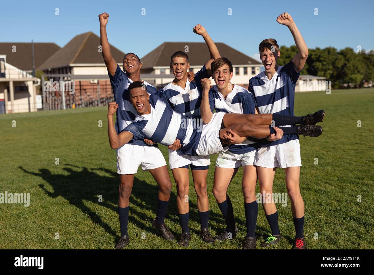 Jugadores de rugby que llevan a su compañero de equipo Foto de stock