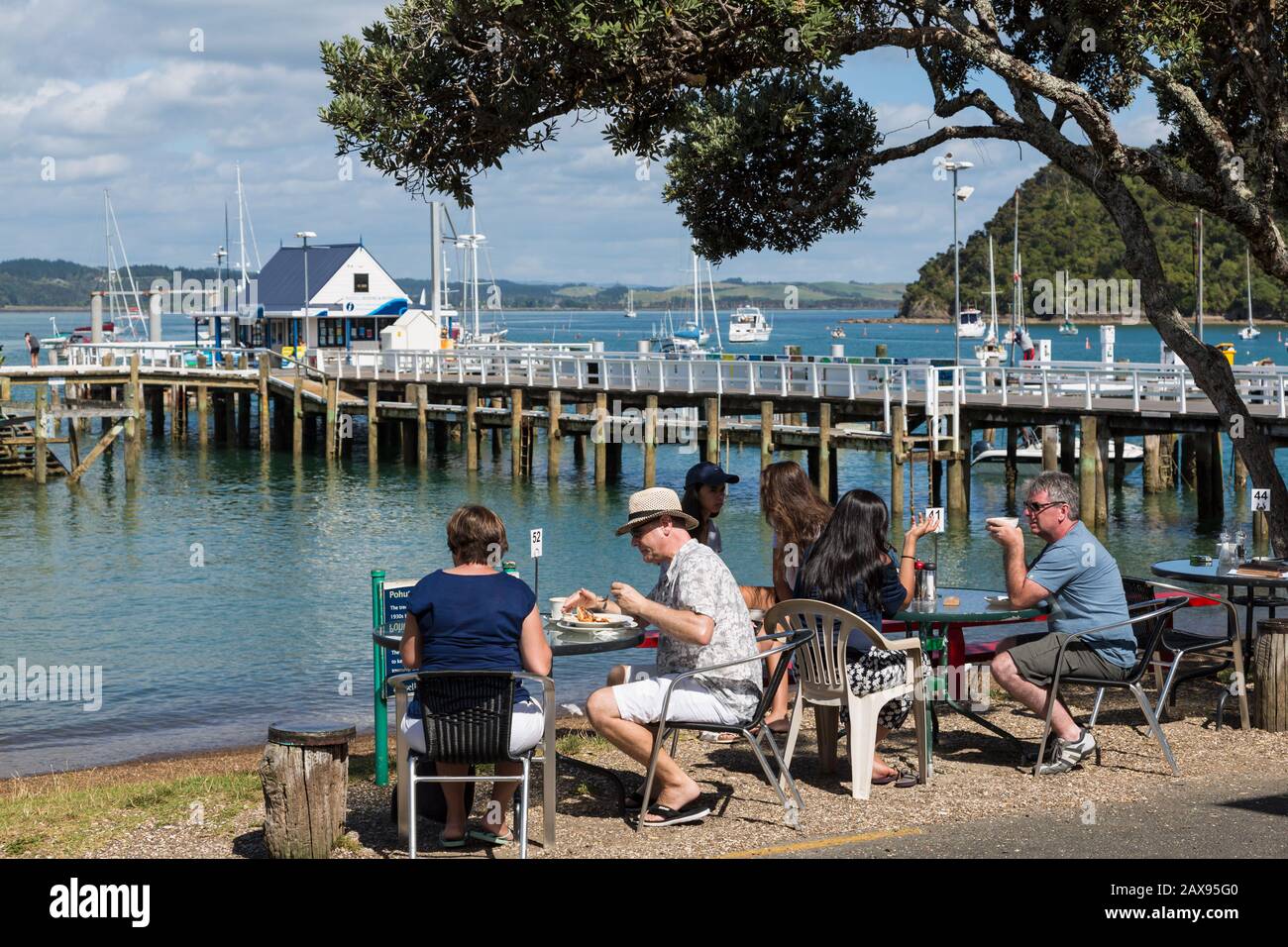 La gente come en la cafetería frente a la playa, Russell, Bay of Islands, Nueva Zelanda Foto de stock