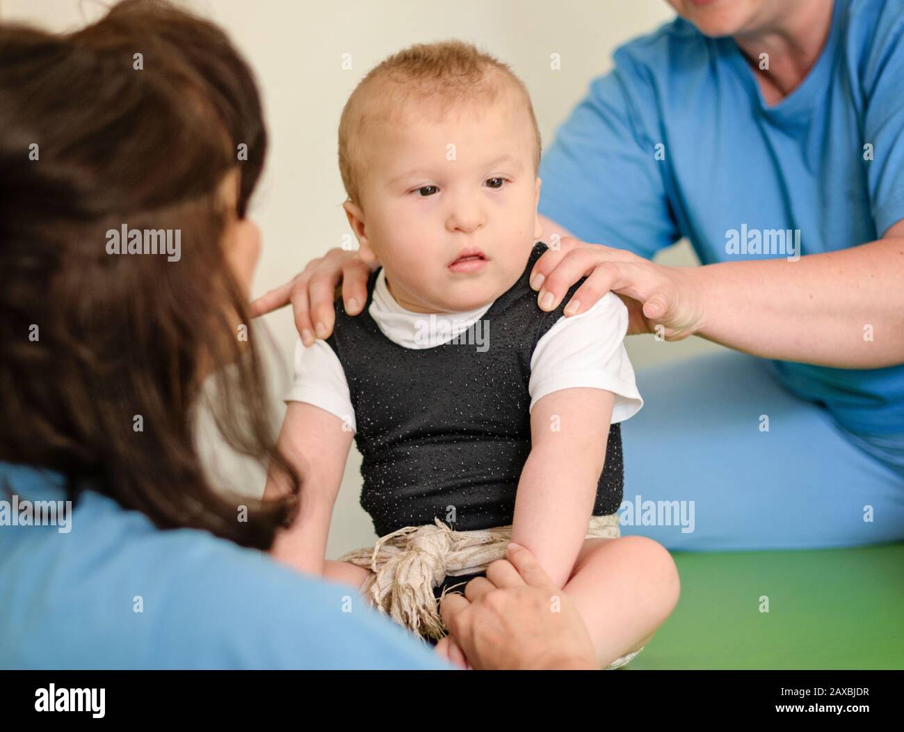 Retrato de un bebé con parálisis cerebral en fisioterapia en un centro de terapia infantil. Niño con discapacidad haciendo ejercicios con fisioterapeuta. Foto de stock