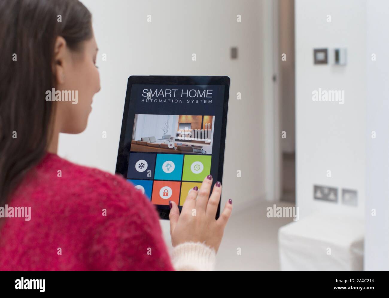 Mujer que utiliza un sistema inteligente de automatización doméstica con tableta digital Foto de stock