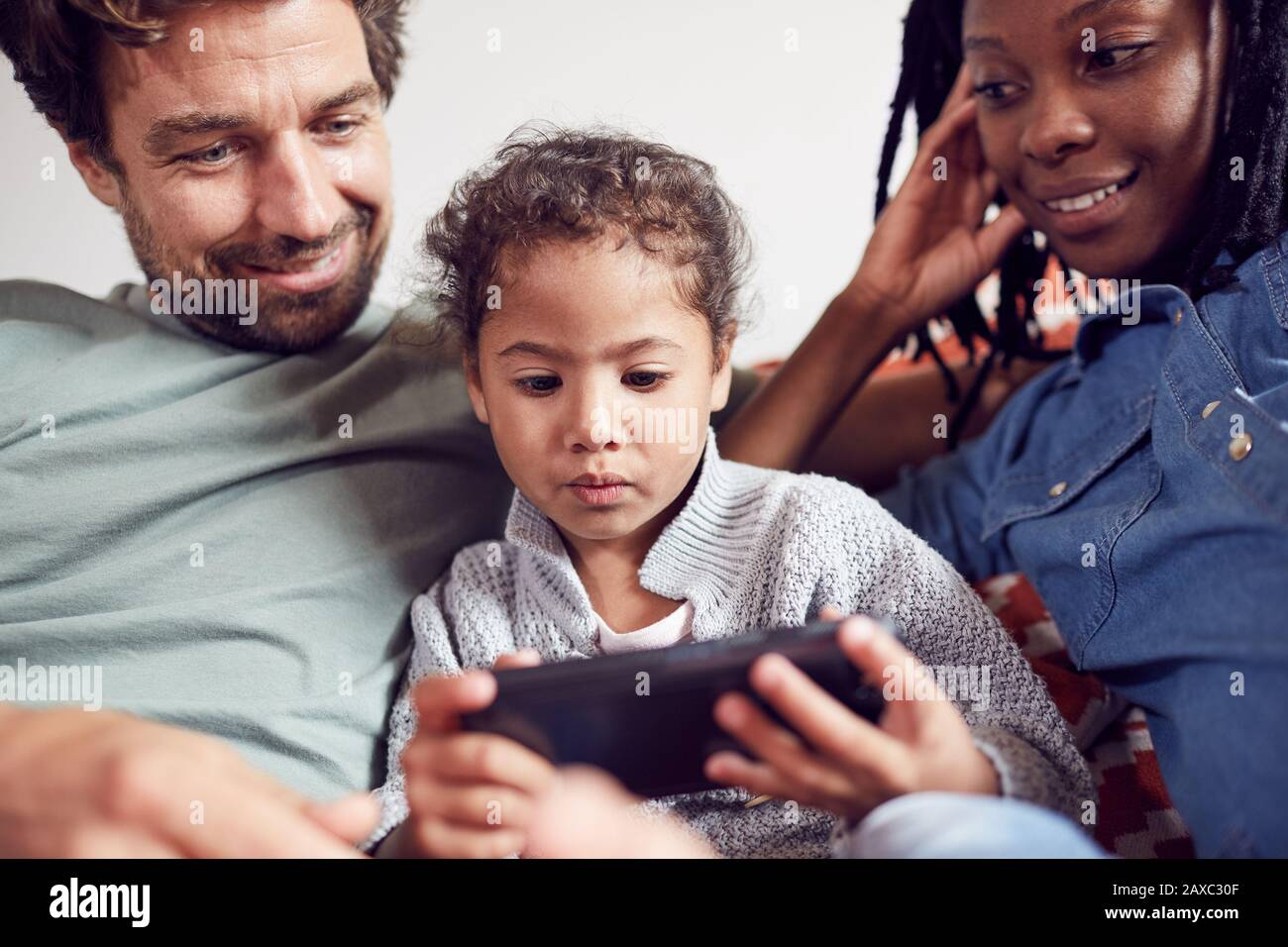 Familia joven utilizando el teléfono inteligente Foto de stock