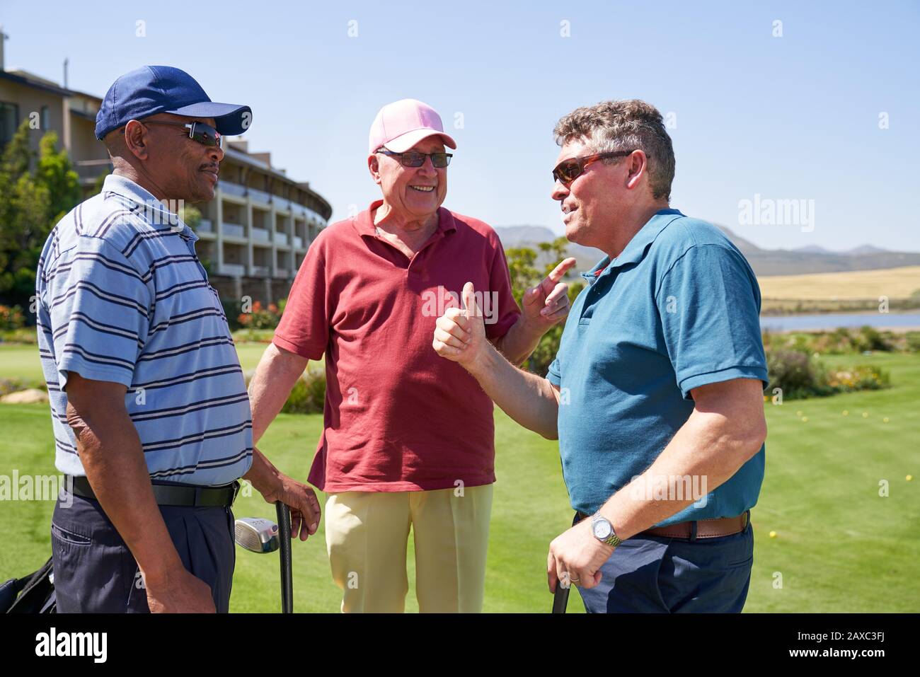 Feliz hombre golfista amigos hablando en el campo de golf soleado Foto de stock