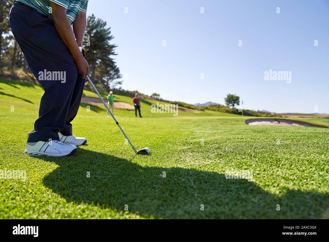 Golfista masculino tomando un tiro en el campo de golf soleado Foto de stock