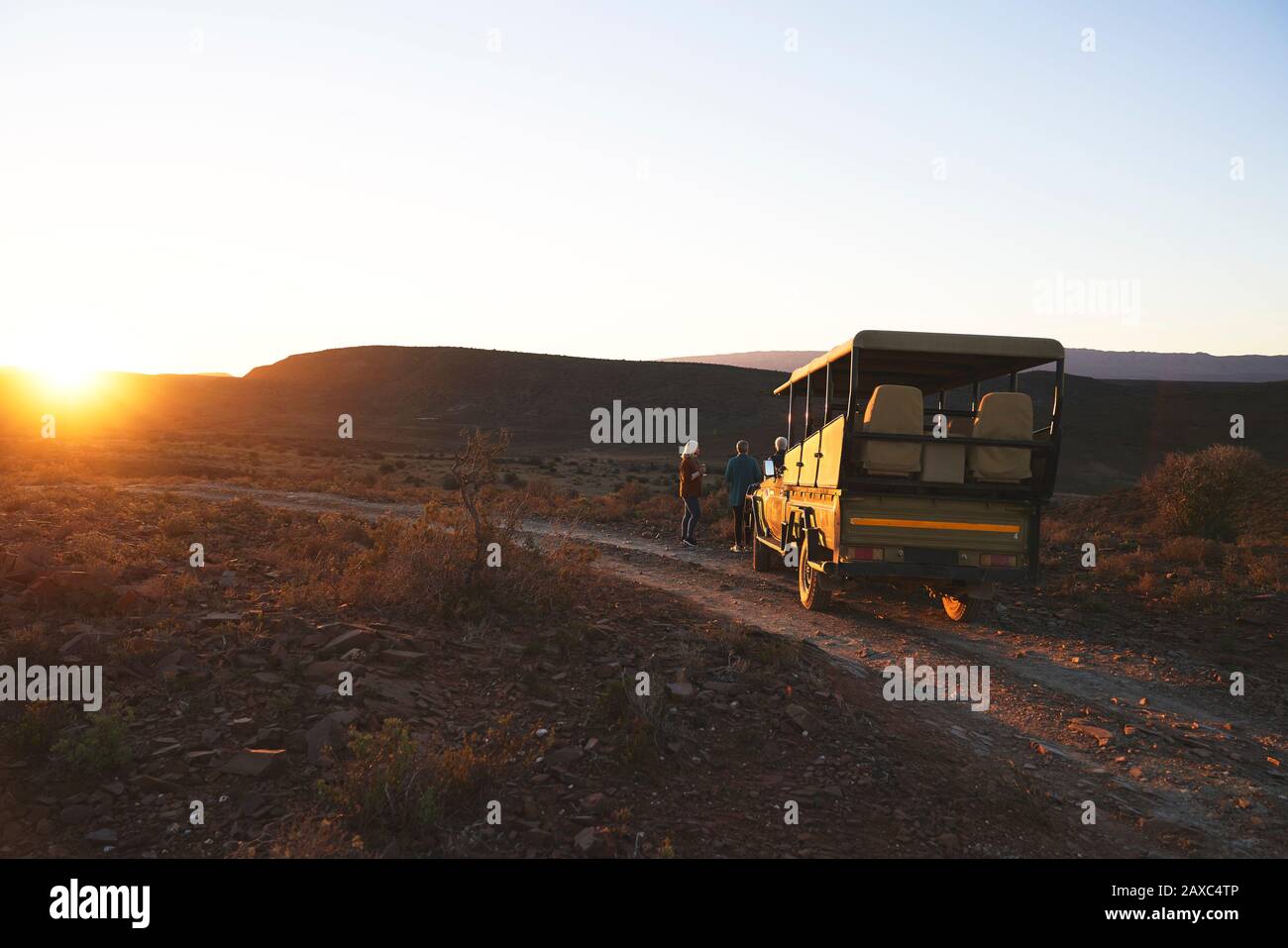 Safari en vehículo todoterreno y turistas en la puesta de sol carretera Sudáfrica Foto de stock