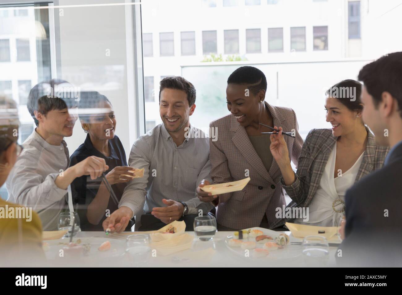 Feliz gente de negocios disfrutando de sushi almuerzo Foto de stock