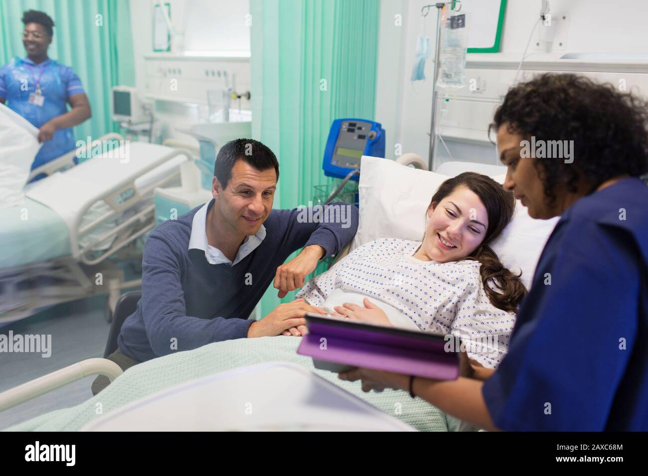 Doctor con tabletas digitales haciendo rondas, hablando con una pareja en la sala del hospital Foto de stock