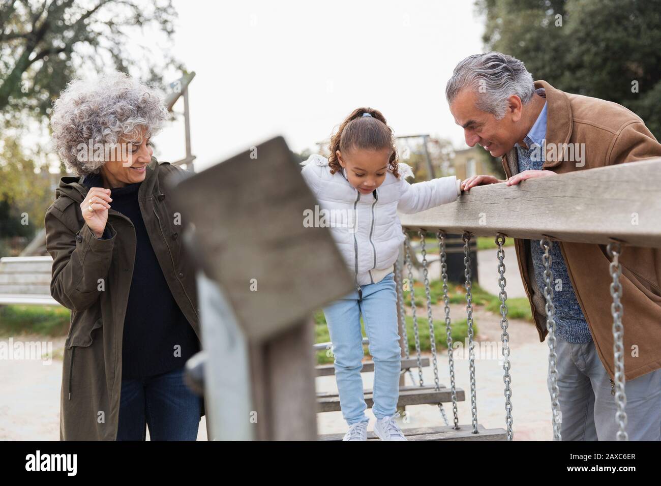 Abuelos y nieta jugando en el patio de recreo Foto de stock