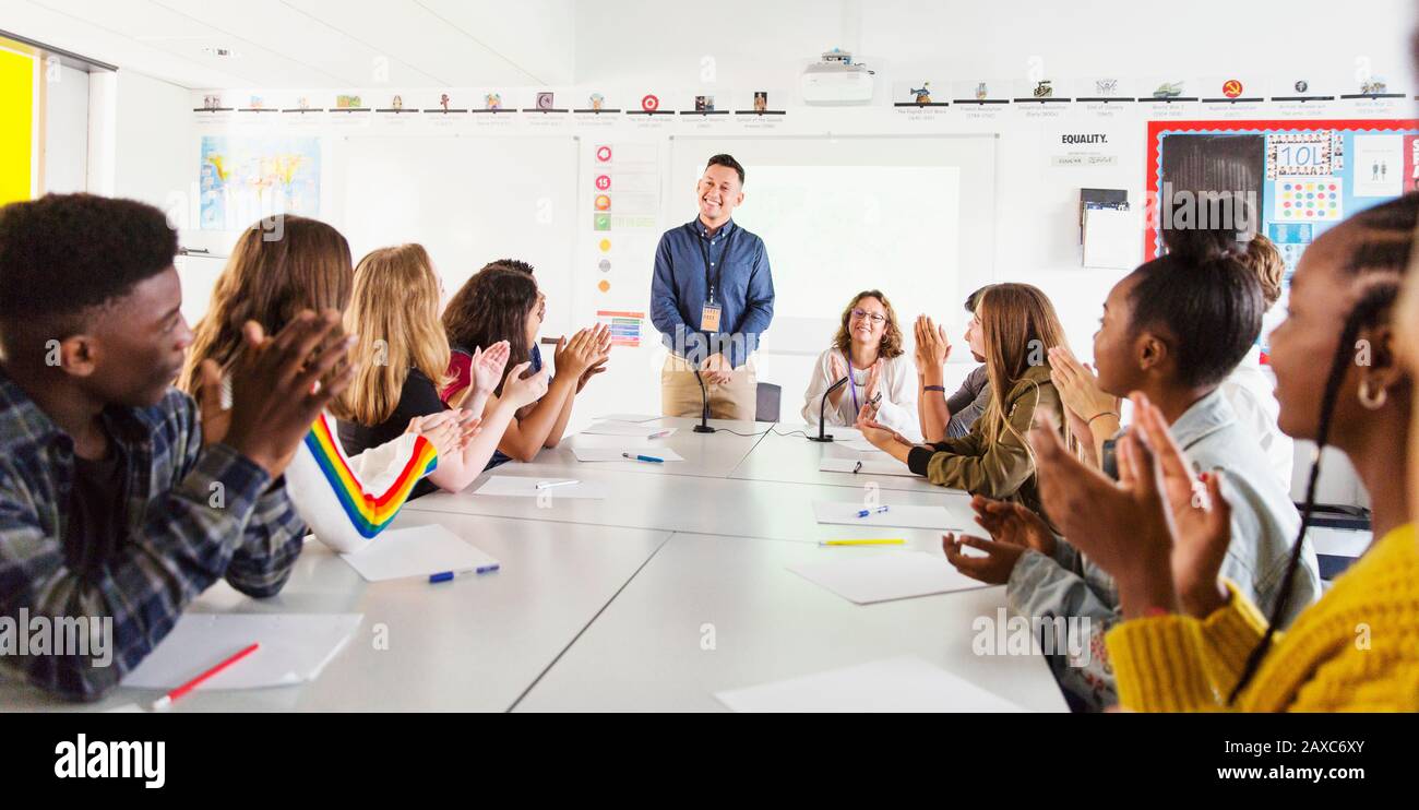 Estudiantes de secundaria aplaudiendo al maestro en clase de debate Foto de stock