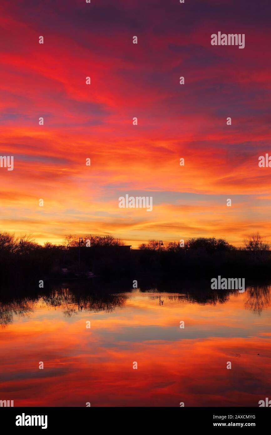 El colorido cielo de la puesta de sol y las espectaculares nubes con reflejo en un lago Foto de stock
