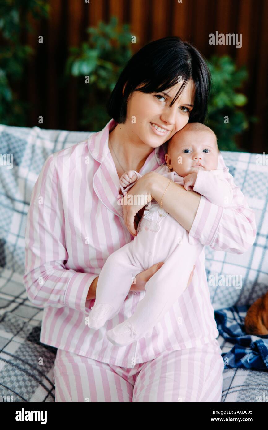 blanco Quedar asombrado Arreglo Una madre en pijama se sienta en un sofá y sostiene a un bebé en sus brazos  Fotografía de stock - Alamy