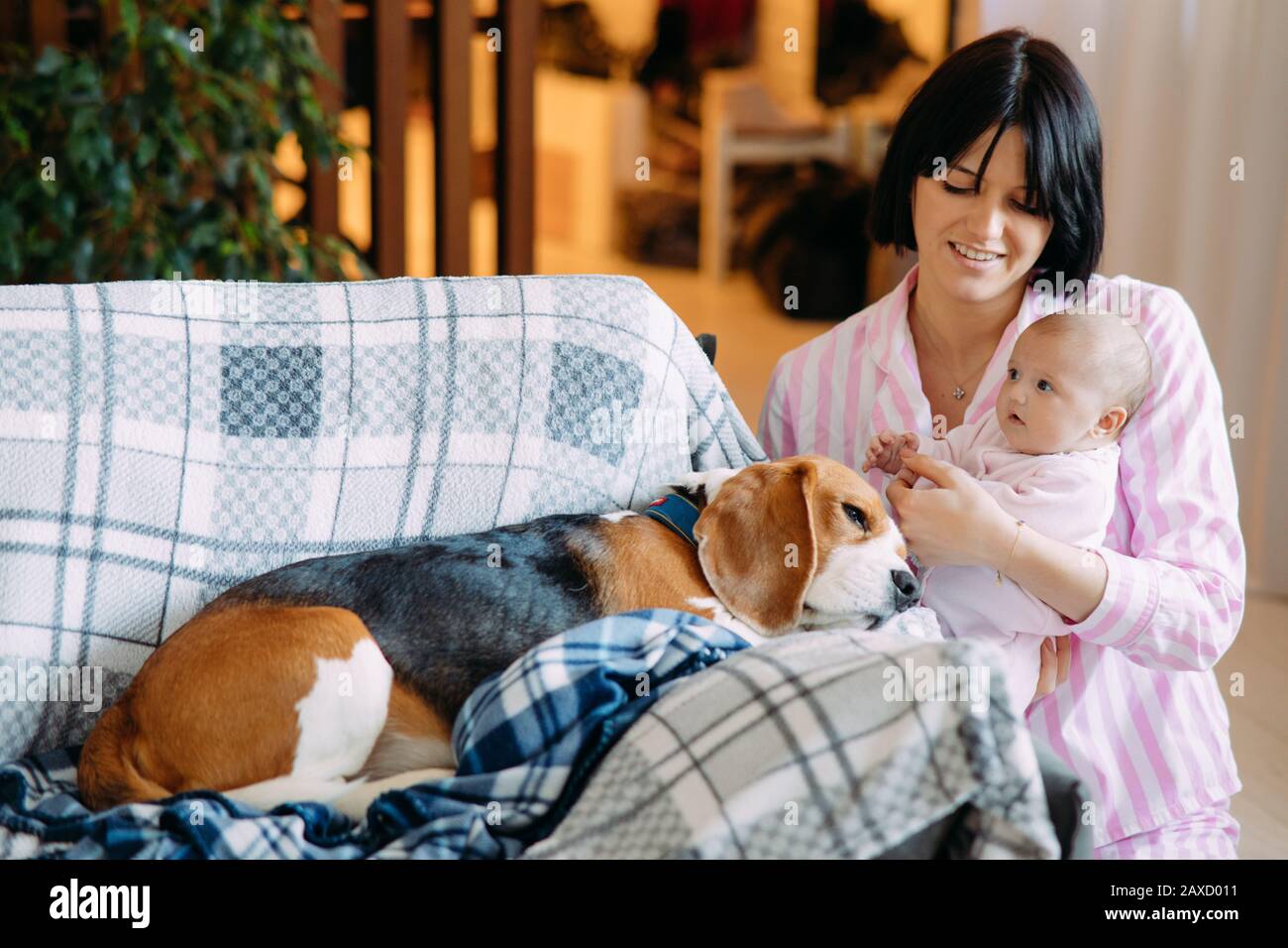 Una madre en pijama sostiene un bebé en sus brazos al lado de un sofá cama Fotografía de stock - Alamy