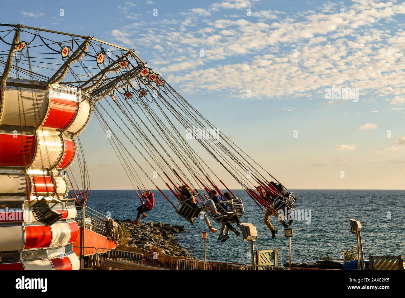 Carrusel de sillas voladoras en movimiento en el parque de atracciones en  la costa de Sanremo en la Riviera di ponente con fondo de mar y cielo,  Liguria, Italia Fotografía de stock -
