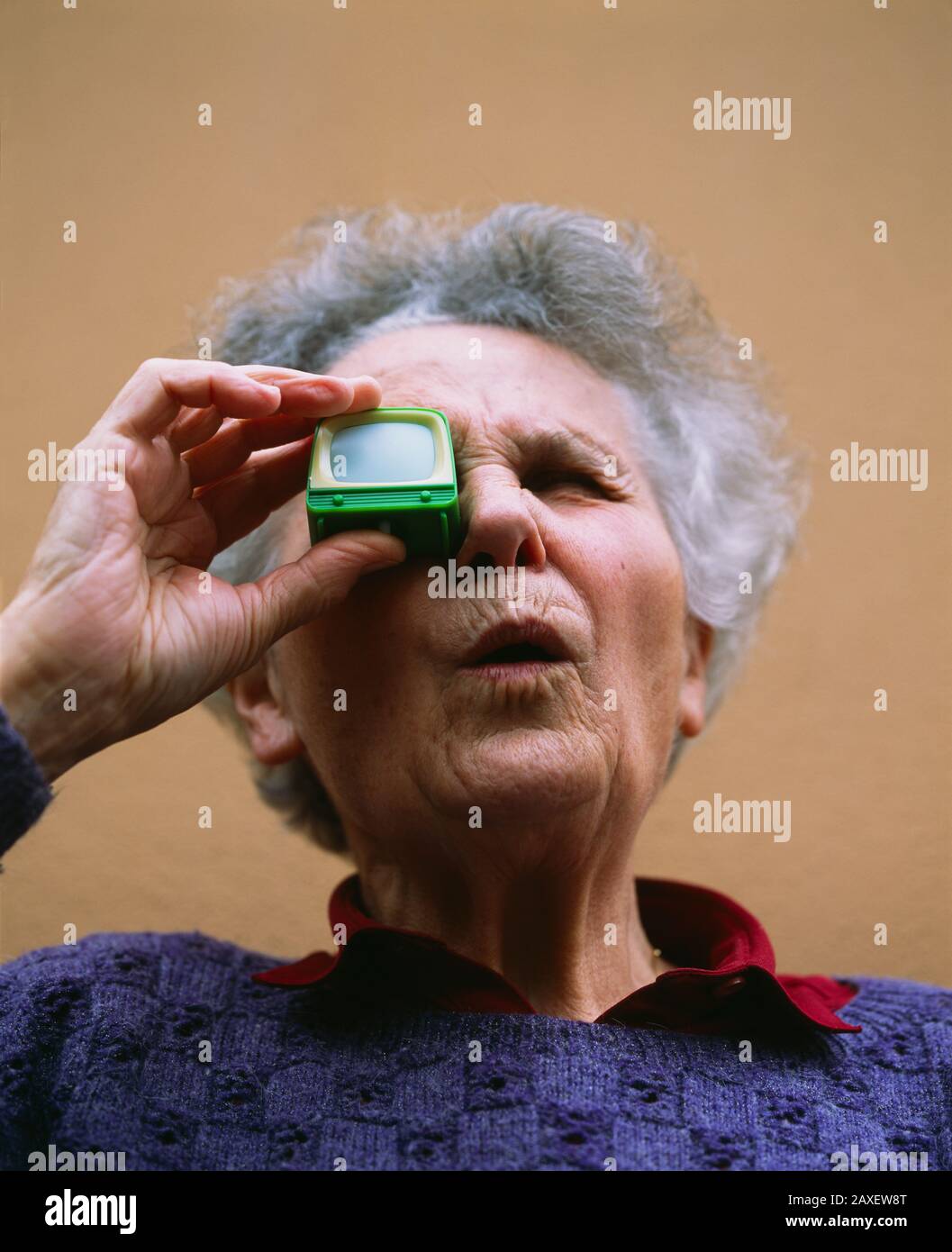 Vista en ángulo bajo de una mujer mayor mirando a través de un espectador de televisión, Alemania Foto de stock