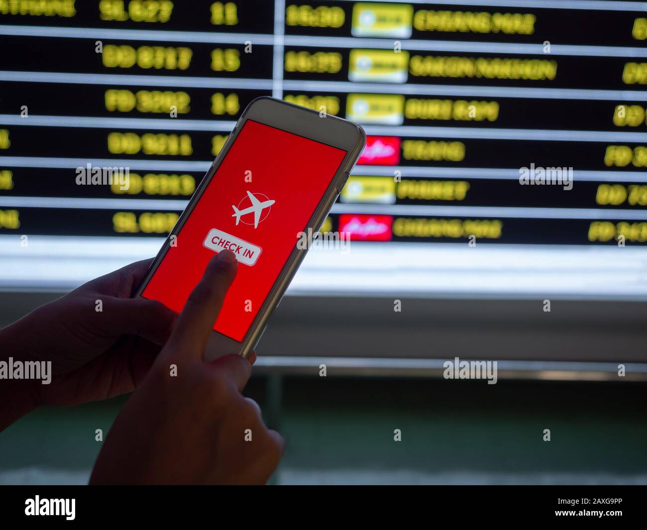 Facturación de vuelos por teléfono móvil. Toque con la mano en la pantalla  del smartphone para realizar el check-in de un vuelo delante del fondo de  información de la pizarra de vuelos
