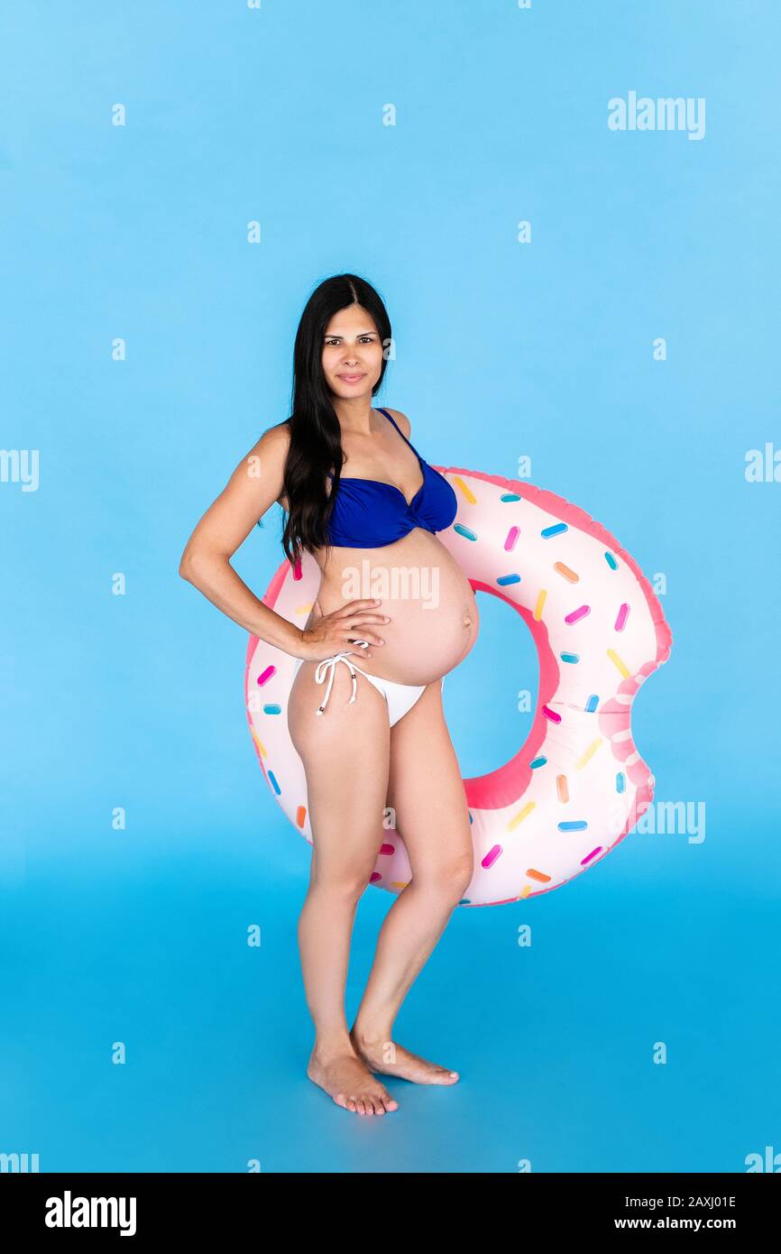 Mujeres embarazadas felices en traje de baño con anillo de natación en un  fondo azul de color Fotografía de stock - Alamy