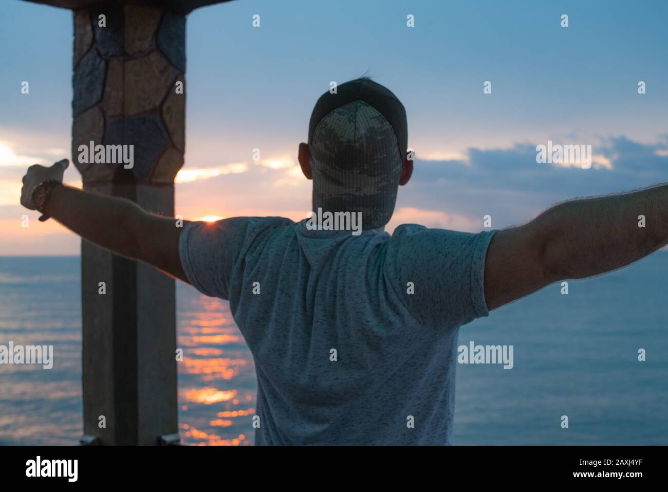 Hombre que abre sus brazos a la vista del mar y encuentra paz. Concepto De Libertad. Foto de stock