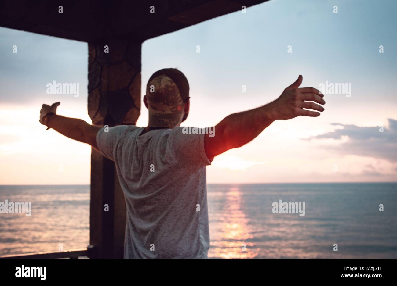 Hombre que abre sus brazos a la vista del mar y encuentra paz. Concepto De Libertad. Foto de stock