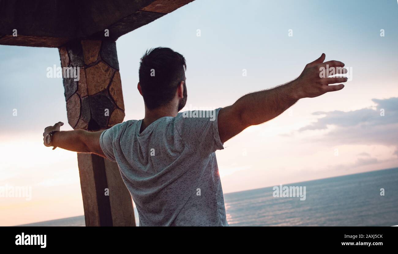 Hombre que abre sus brazos a la vista del mar y encuentra paz. Concepto De Libertad. Foto de stock