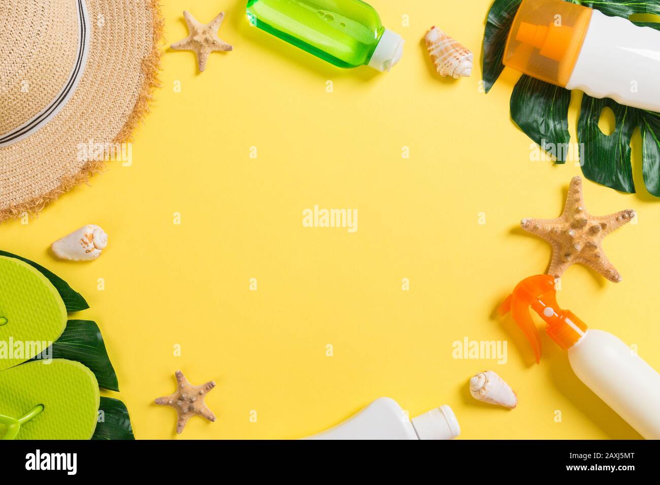 Accesorios de playa con sombrero de paja, bronceador y seastar sobre fondo amarillo vista superior con espacio de copia. Foto de stock