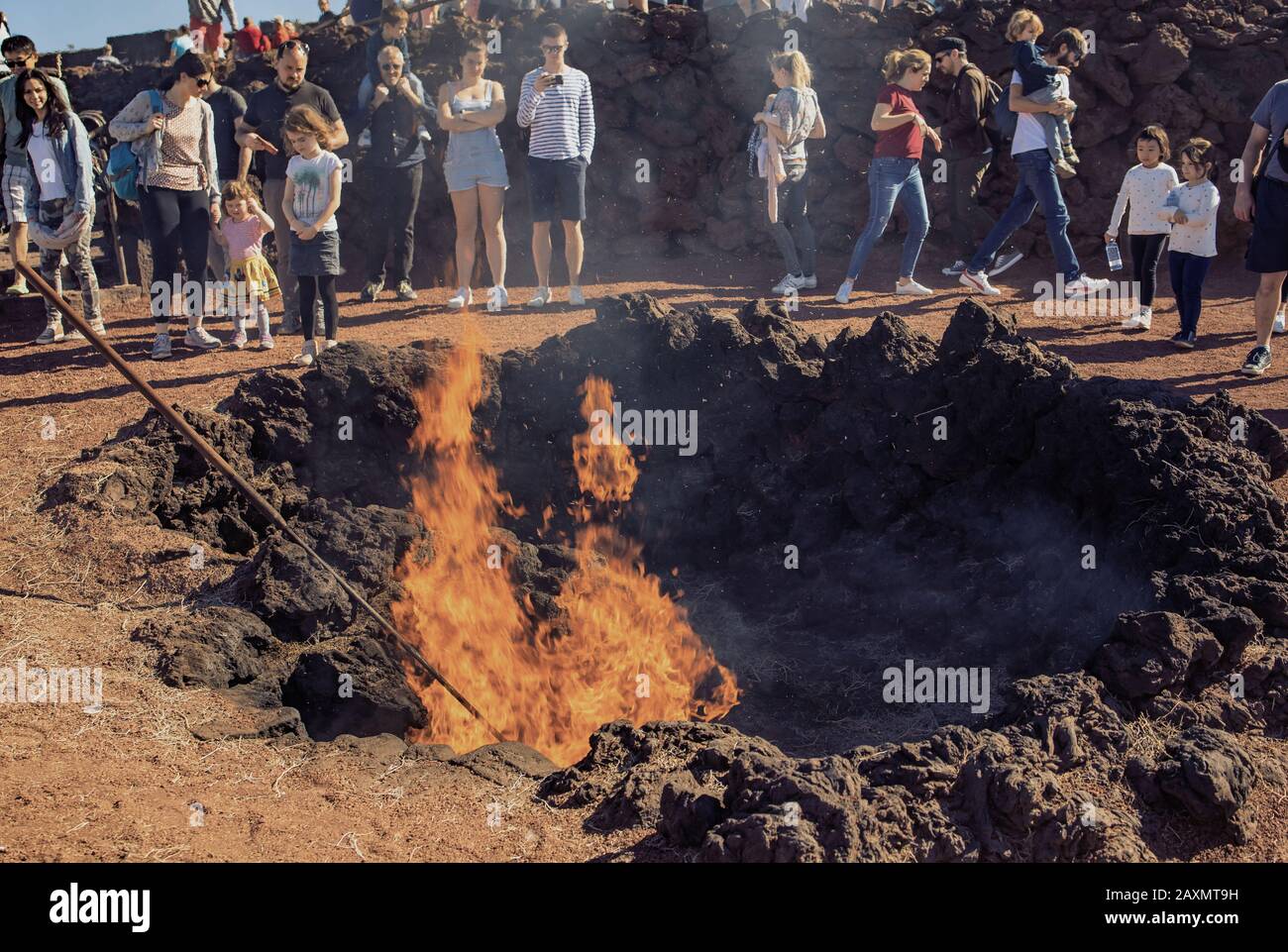Lanzarote, Islas Canarias, España - 28 de diciembre de 2019: El calor del volcán Timanfaya causa fuego caliente de la paca de heno en el Parque Nacional de Timanfaya en Lanzarote. Los turistas están observando el fuego. Foto de stock