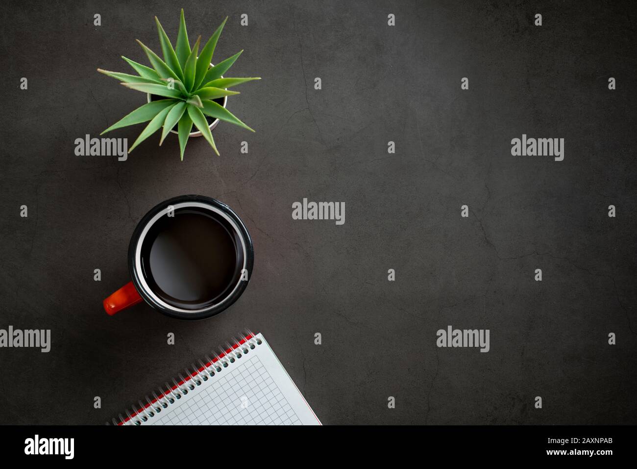 vista superior de mesa con bloc de notas, café y planta sobre fondo negro. Foto de stock