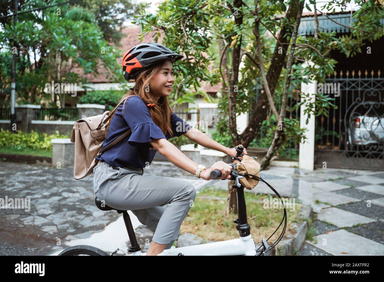 Las mujeres jóvenes montando bicicletas plegables en la carretera con  cascos y maletines para trabajar Fotografía de stock - Alamy