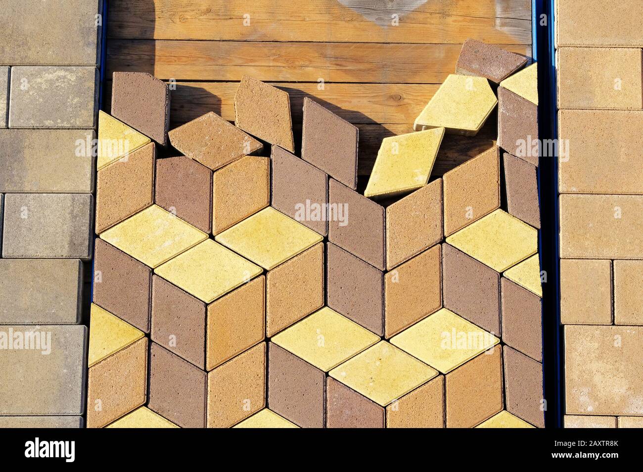 Piedra marrón y amarilla del pavimento en el sitio de la construcción. Losas de pavimentación de almacén para carretera de colocación. Construcción de aceras. Foto de stock