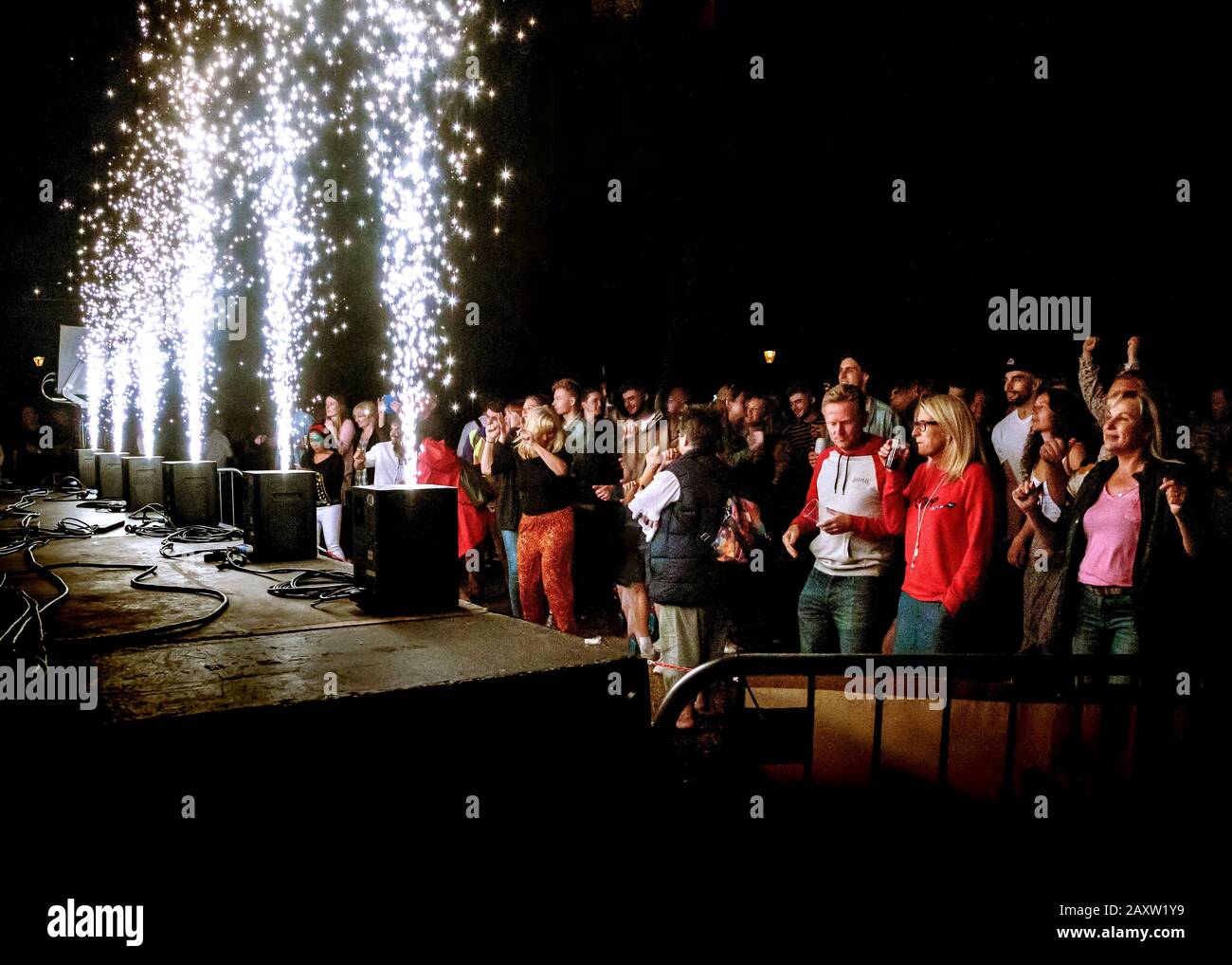 Festival de la audiencia en el exterior por la noche con fuegos artificiales pirotecnia en el escenario Foto de stock