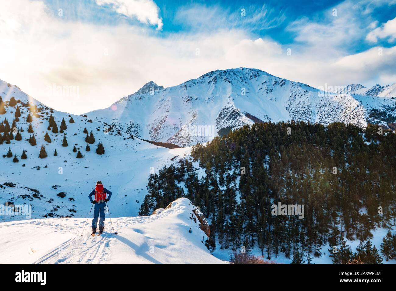 Esquí de gira en un splitboard. Un hombre se encuentra con su espalda al espectador y mira el paisaje de montaña. Deporte de invierno. Kirguistán Foto de stock