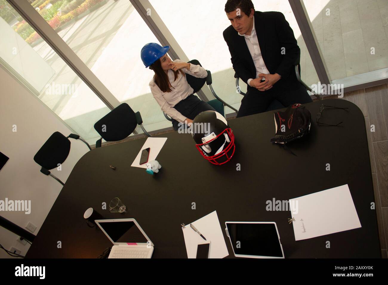 Compañeros de trabajo que piensan en las estrategias a seguir en la sala de trabajo rodeados de herramientas disponibles Foto de stock